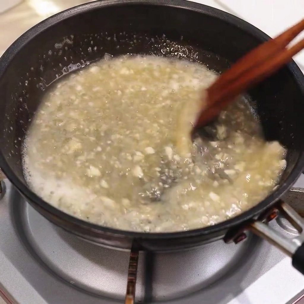 木製のお箸でかき混ぜながら、泡立つパンソースにバターが溶け込んでいる様子。