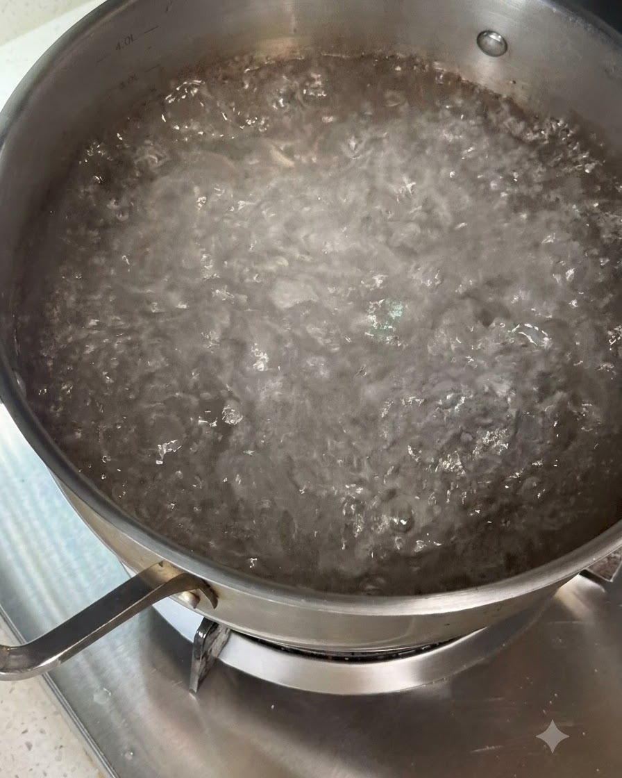 調理器具を使って、乾燥パスタを沸騰したお湯の入った鍋にかき混ぜながら入れている様子。