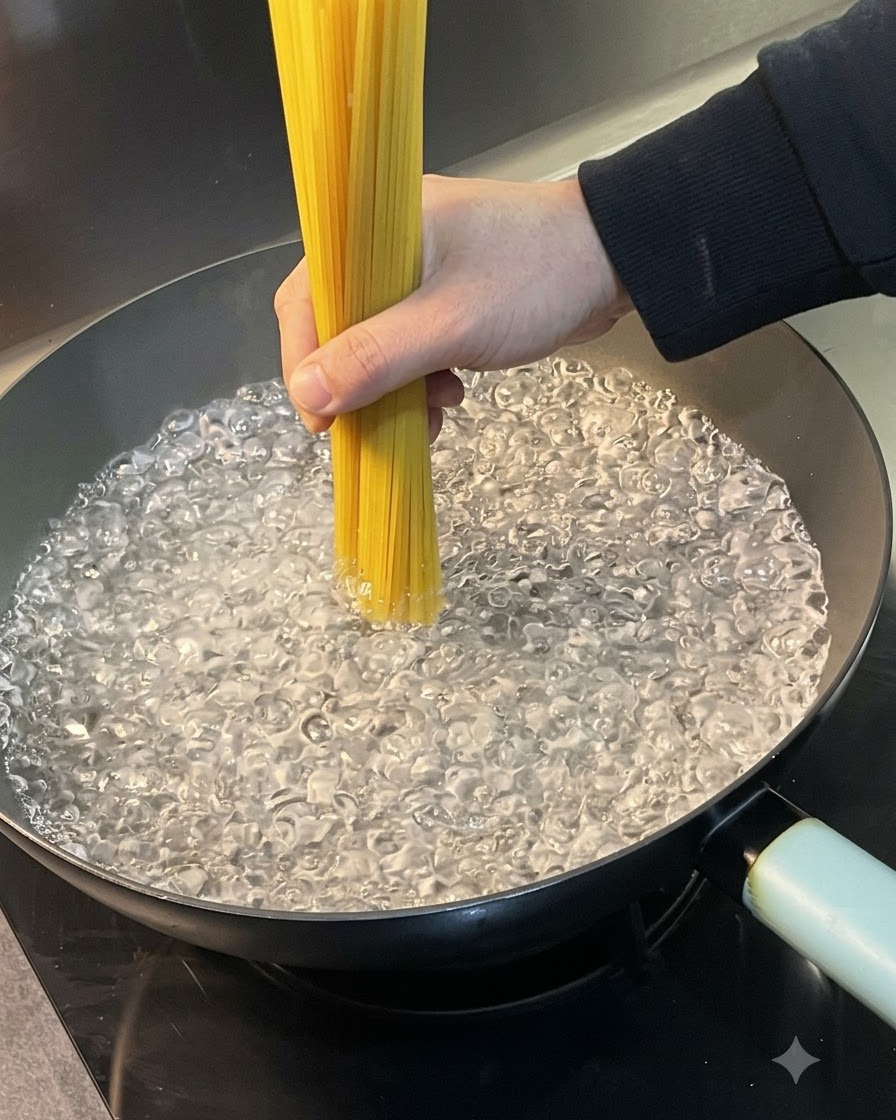 沸騰したお湯の入った鍋に、束になった生スパゲッティを入れている様子。