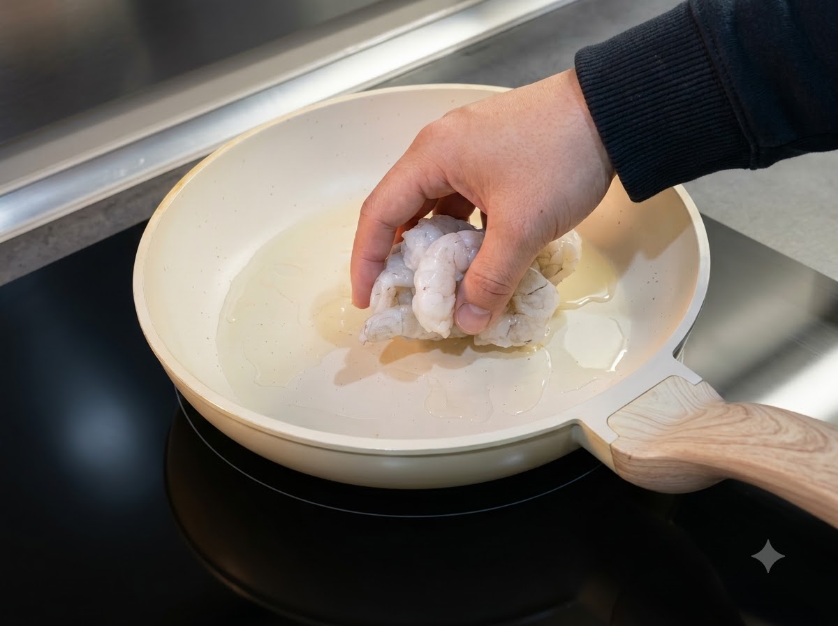 油をひいたフライパンに解凍したエビを並べて焼いている様子。