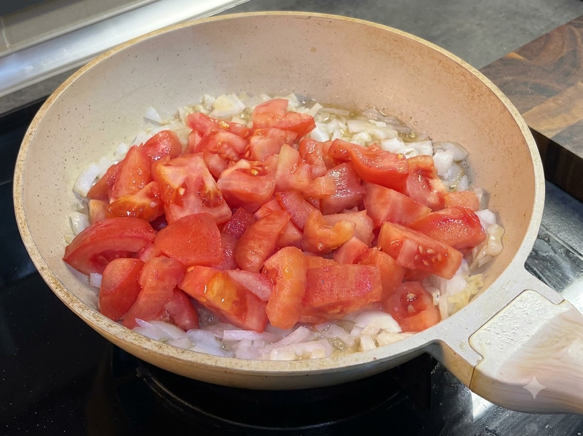 トマトと玉ねぎが入ったフライパンにケチャップを加えている様子。
