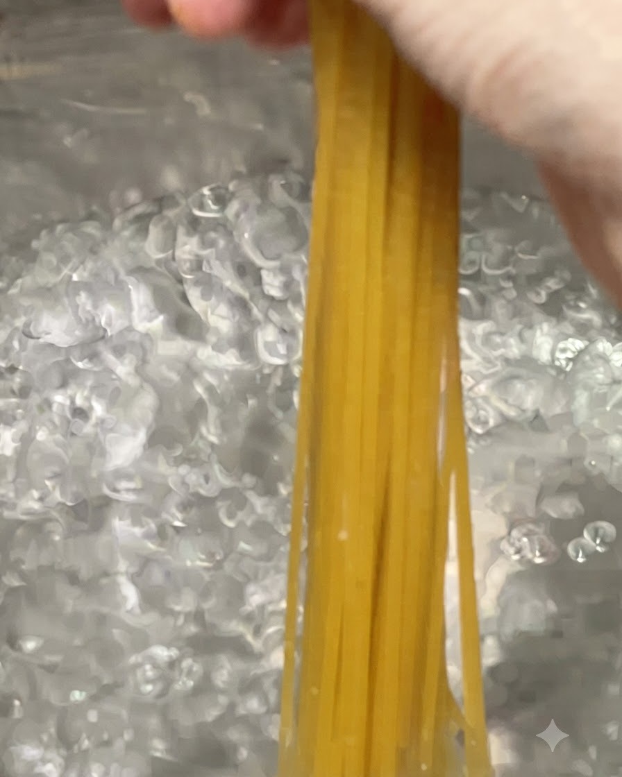 大きな沸騰したお湯の鍋に、スパゲッティの麺が投入されている様子。