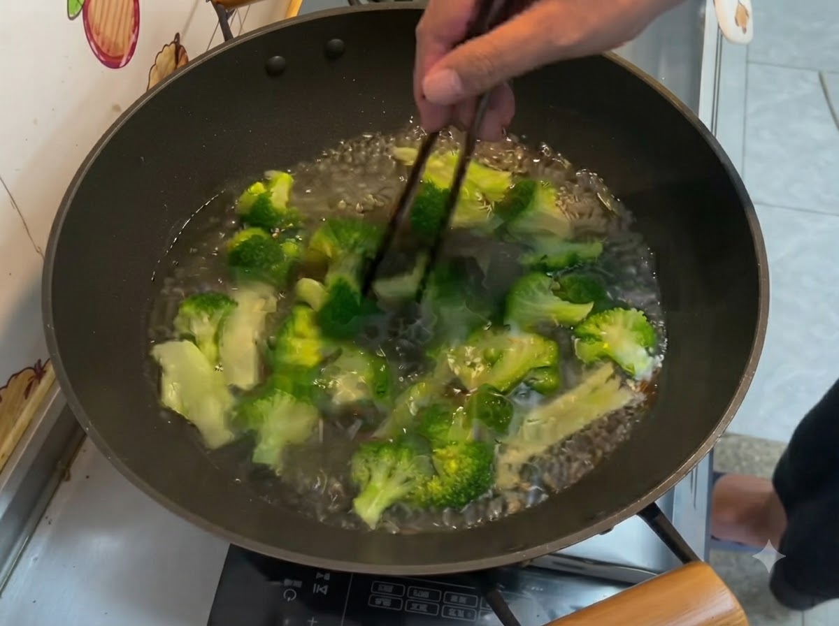 中華鍋の中の沸騰したお湯で茹でられている鮮やかな緑色のブロッコリーの小房を箸で混ぜているところ。
