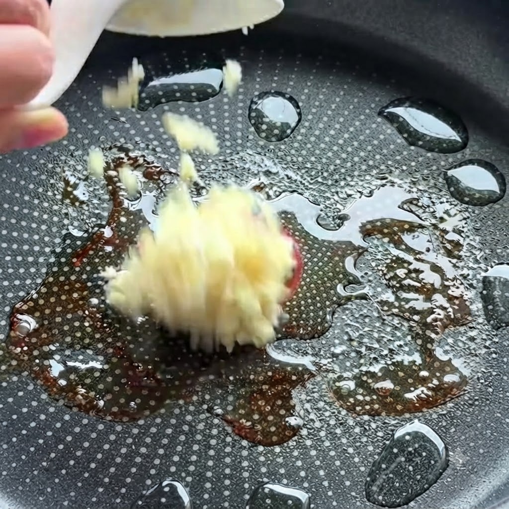 オイルの入った熱したフライパンに、みじん切りにんにくを入れているところ。