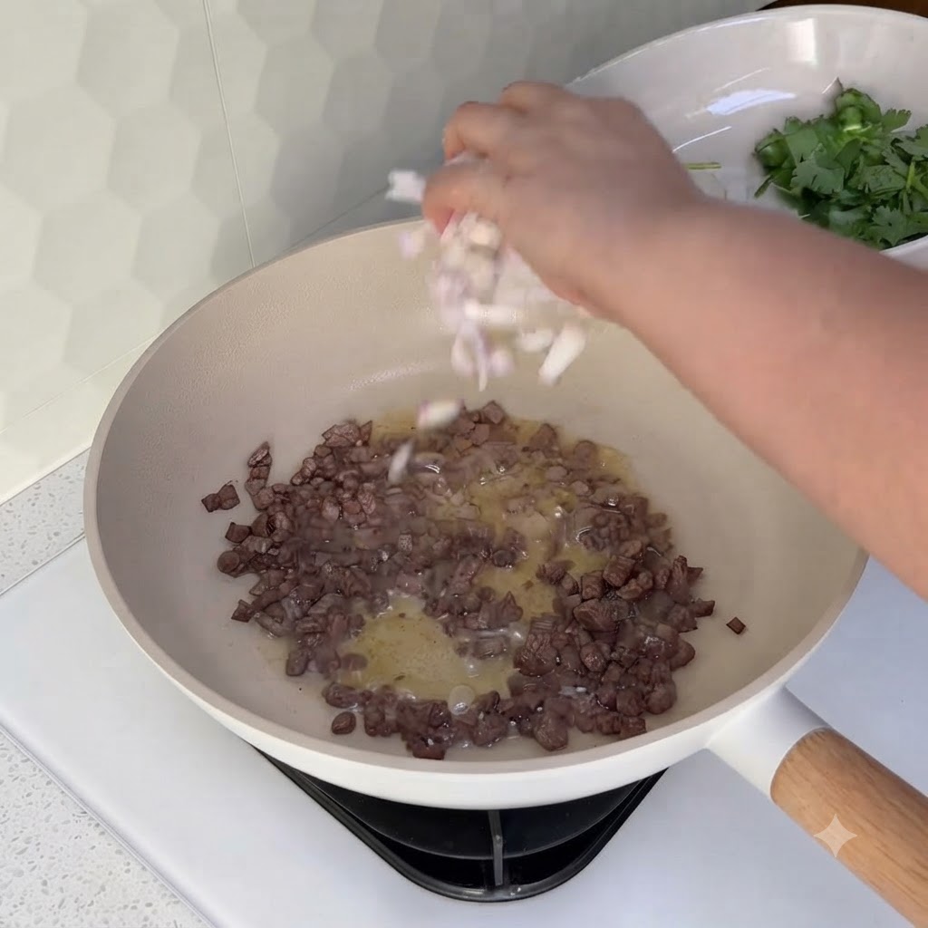 炒めた牛ひき肉が入った中華鍋に、角切りの玉ねぎが加えられている様子。
