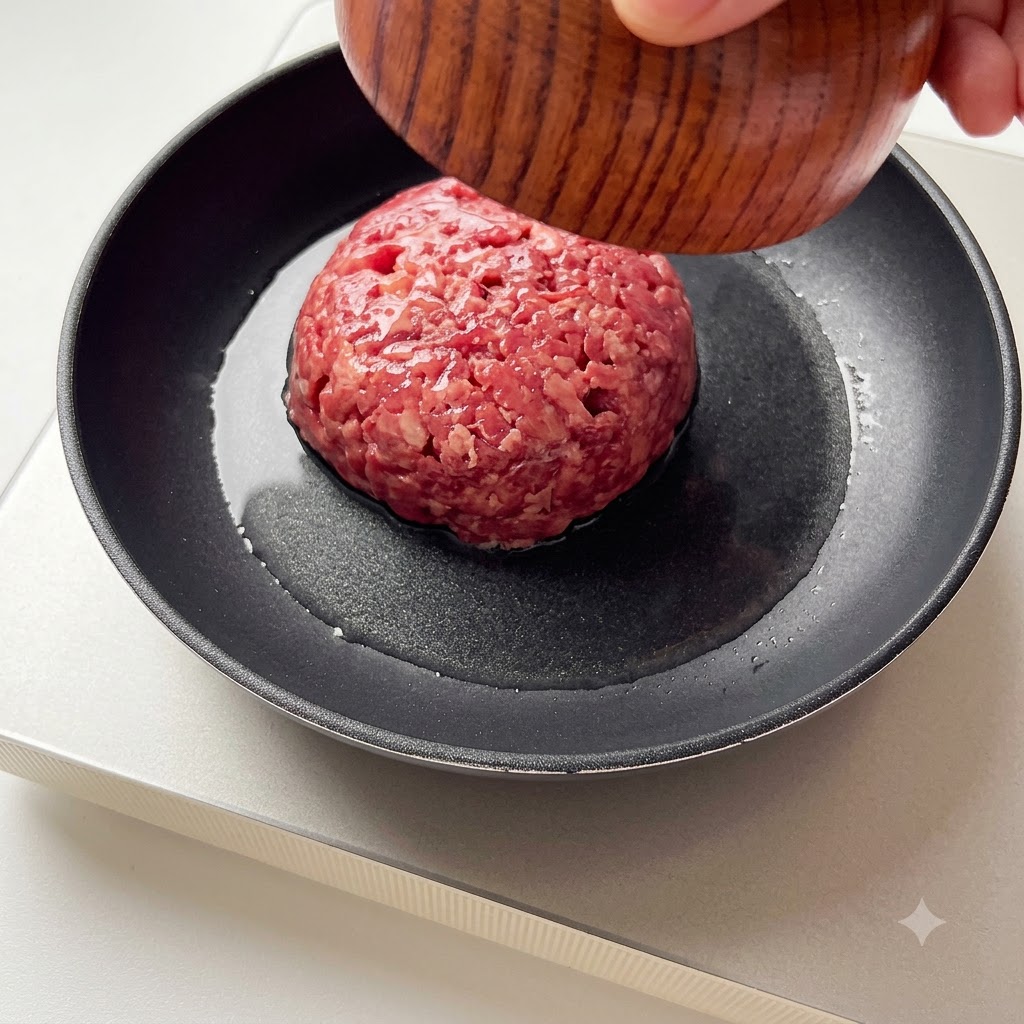 熱したフライパンに牛ひき肉が投入されている様子。