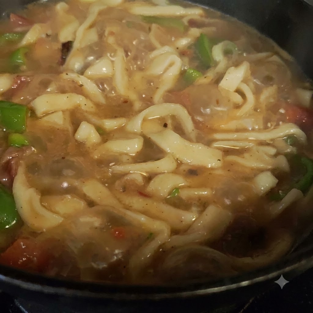 刻んだピーマンとトマトが、調理中の鍋の中でお肉と混ざり合っている様子。