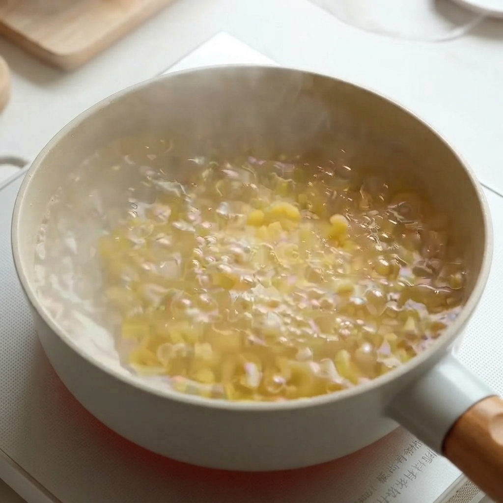 コンロ上の鍋の中で、お湯に浸かったマカロニパスタがぐつぐつと茹でられている様子。