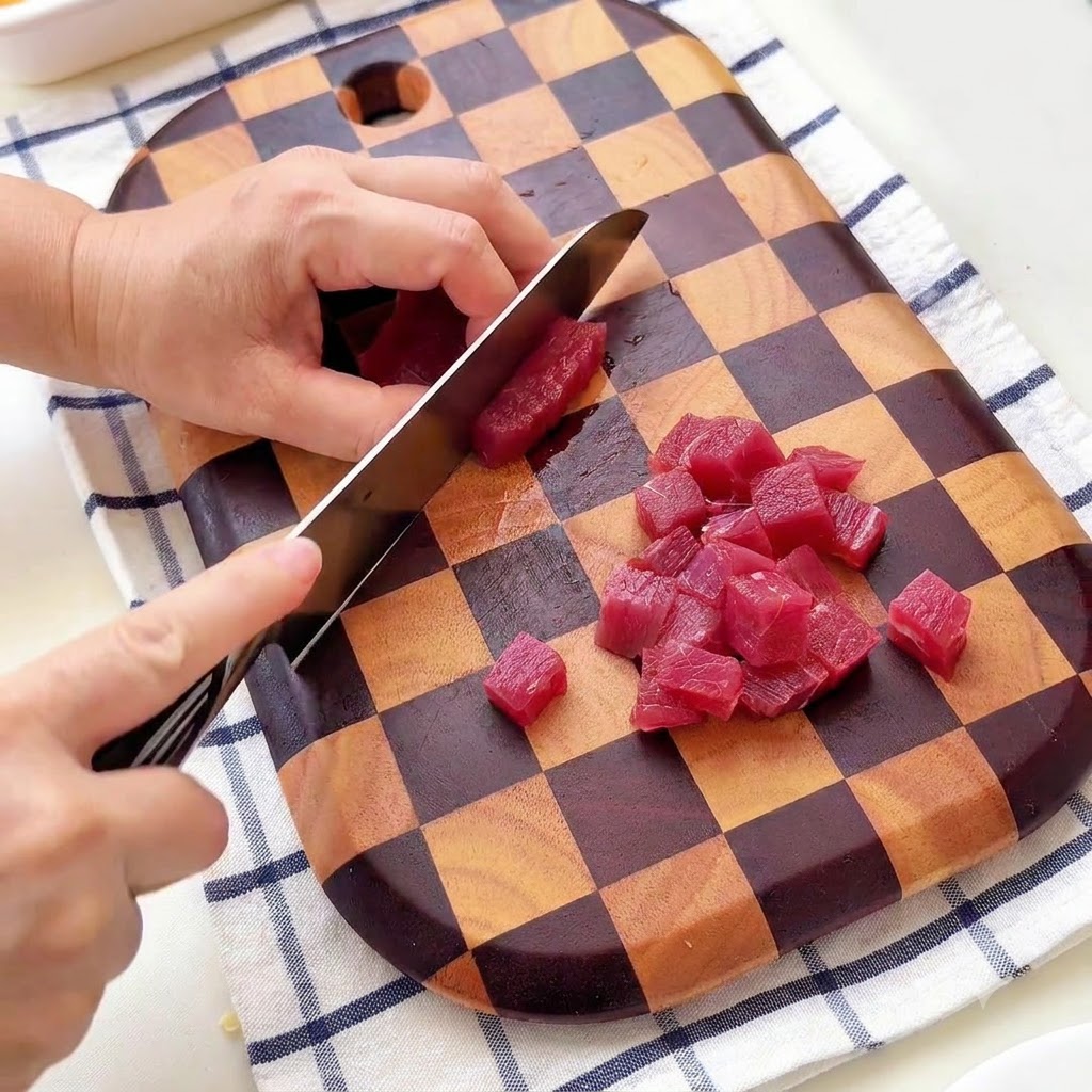 カッティングボードの上で牛肉を小さめの角切りにしている様子。