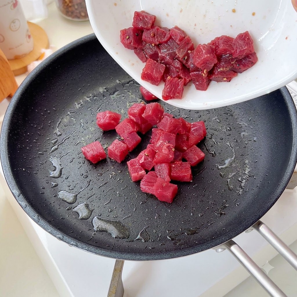 下味をつけた牛肉をフライパンに入れ、炒めている様子。