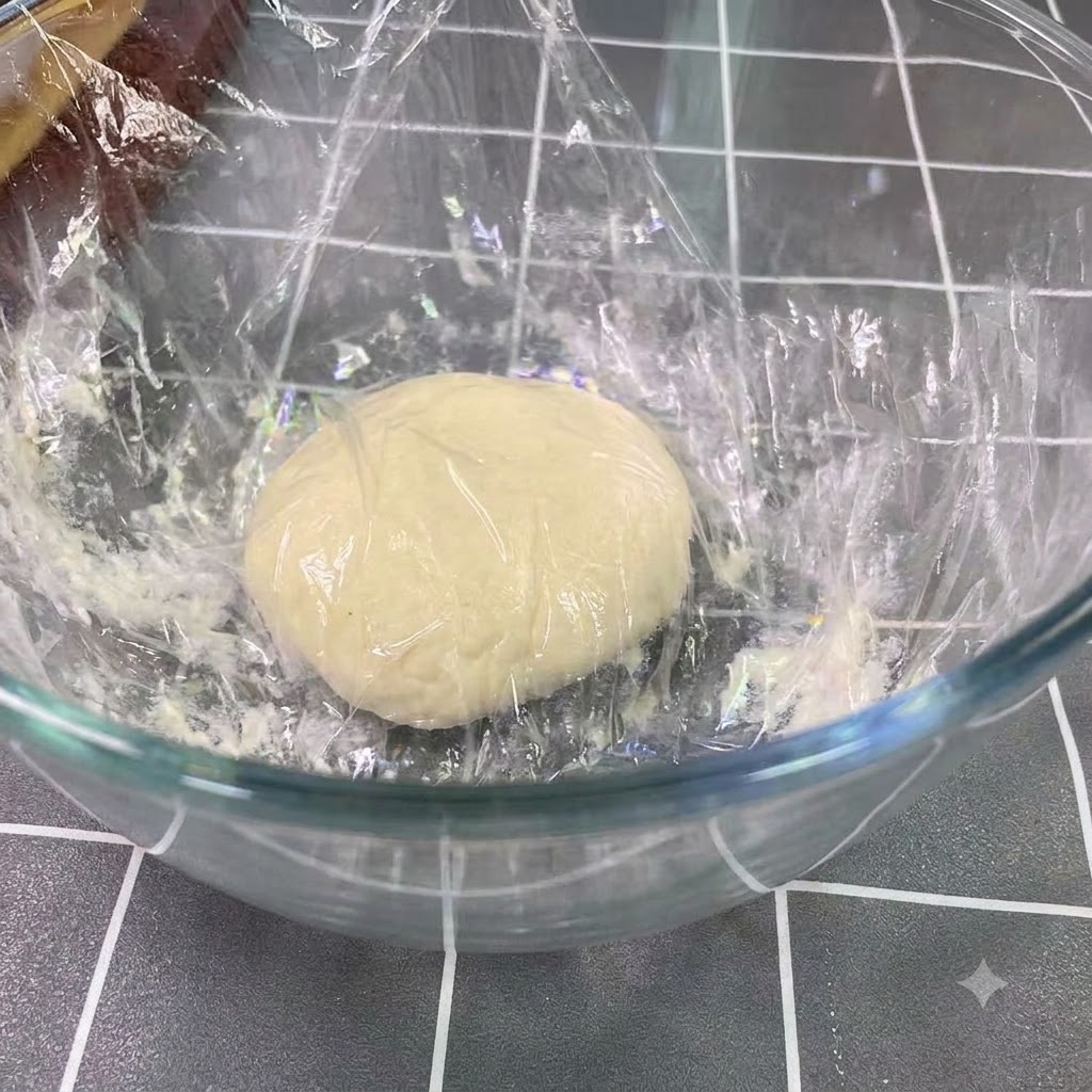 大きなガラスボウルの中で2倍の大きさに膨らんで休ませている発酵中の生地。