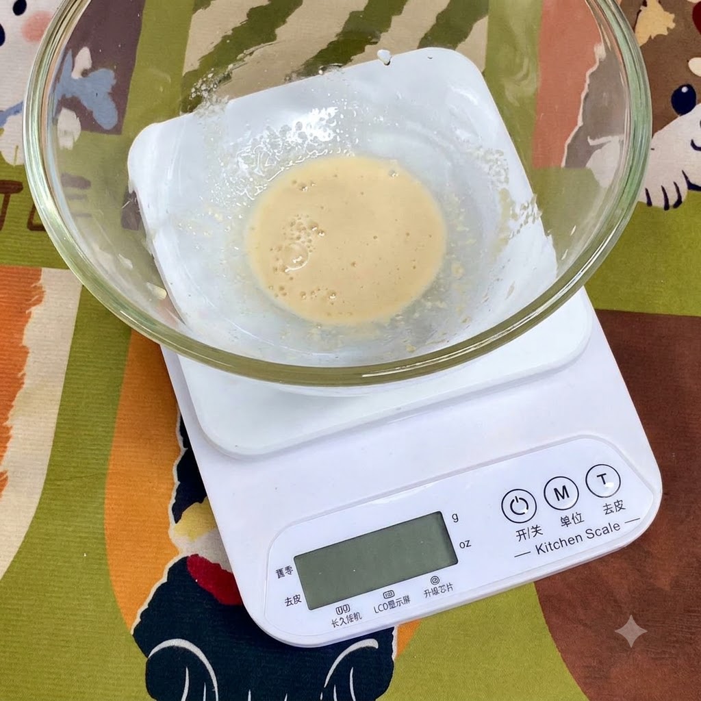 デジタルキッチン秤の上に置かれたガラスボウルの中で、小麦粉、塩、オリーブオイルなどの計量された材料。
