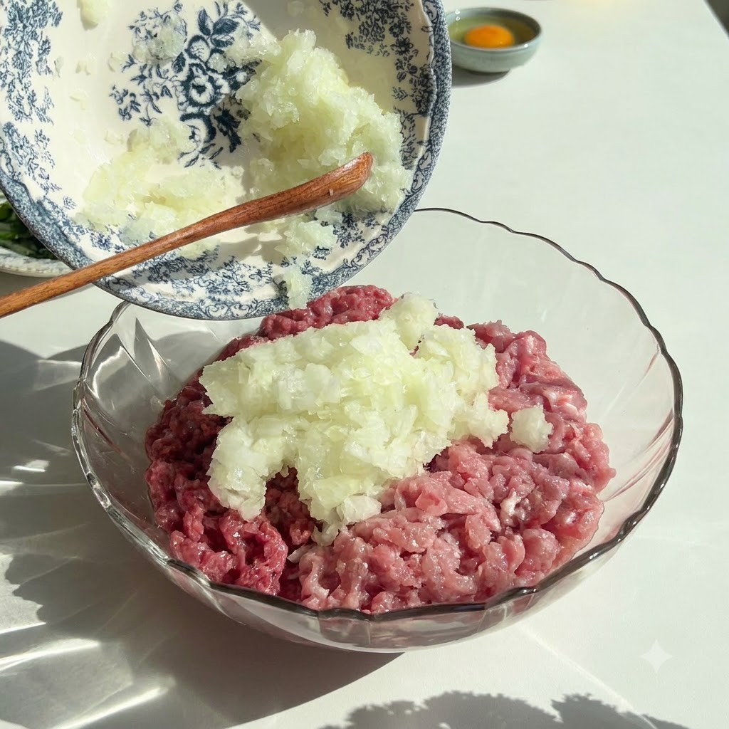みじん切りにした玉ねぎとパセリが、生のひき肉が入ったガラスボウルに装飾的な器から注がれている様子。