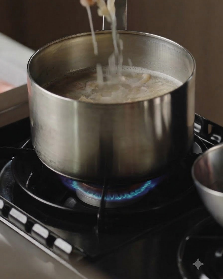 沸騰したスープの鍋から、箸で茹で上がった肉のスライスを持ち上げている様子。