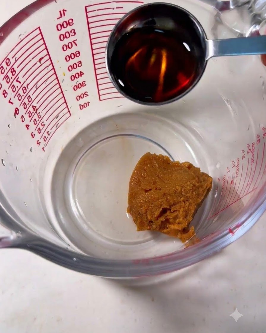 茶色の味噌が入った計量カップにスプーンでみりんを注いでいる様子
