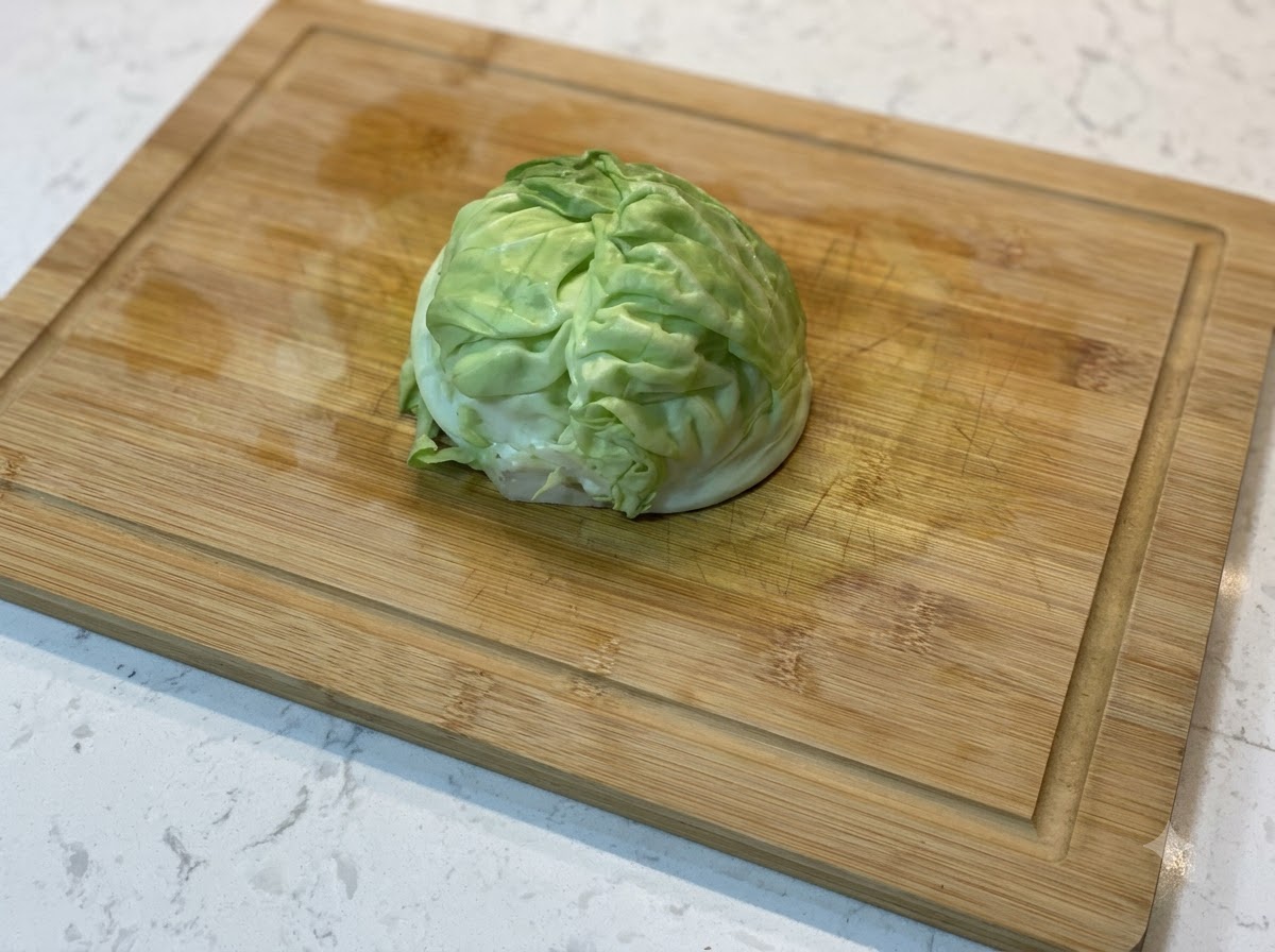 木製のまな板の上に置かれた新鮮なキャベツのくし形切り。