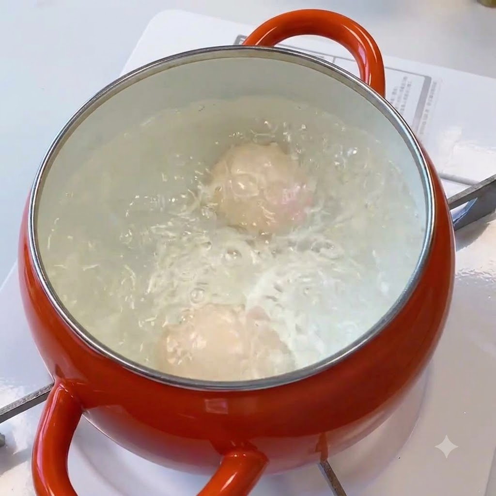 オレンジ色の鍋の中で卵が激しく茹でられている様子。