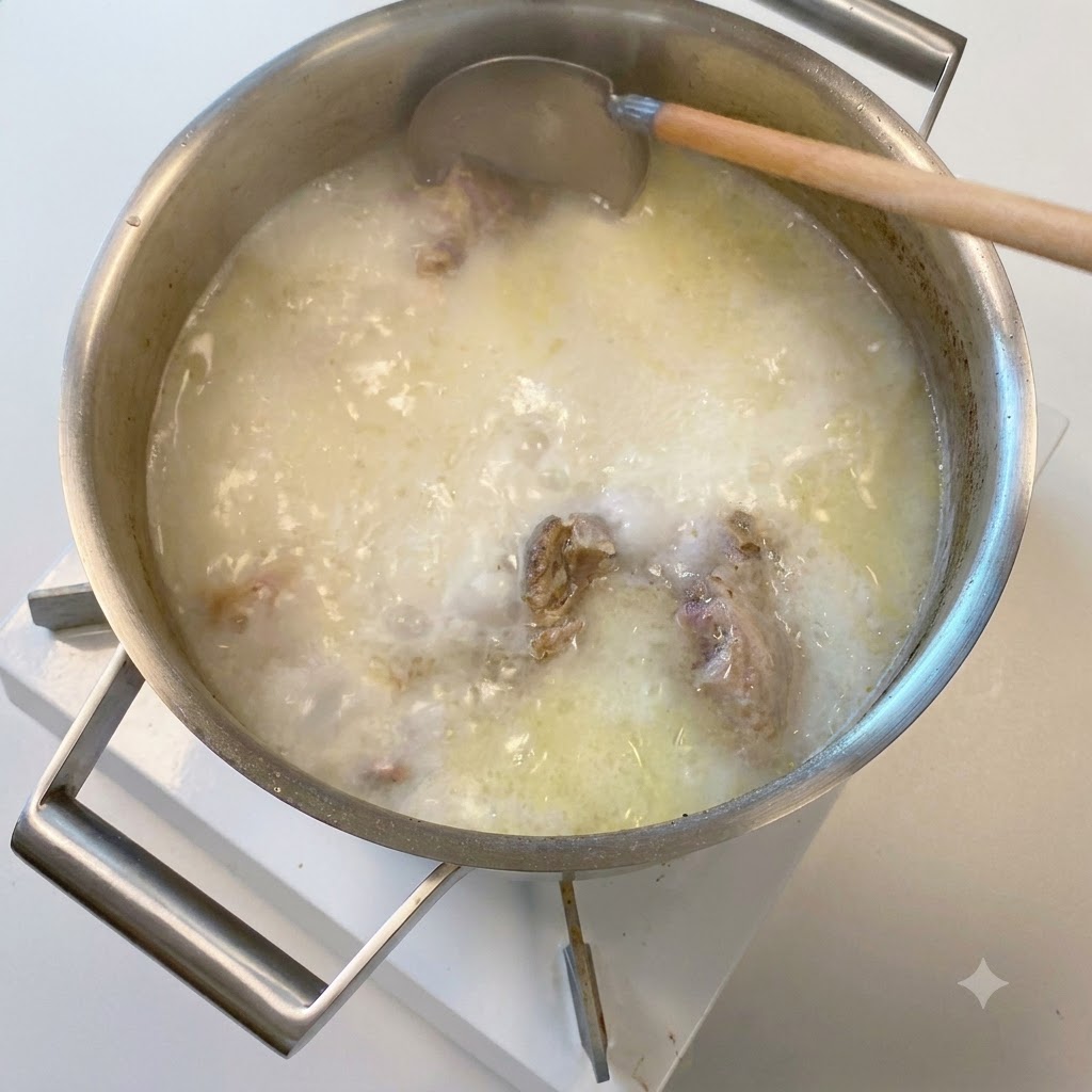 木製のお玉が、乳白色に濁ったスープの鍋からすくい上げている様子。