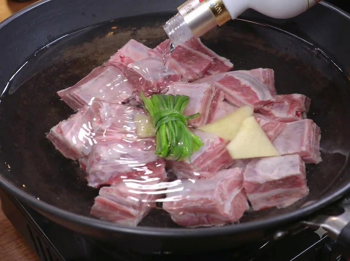 下茹でのため、長ねぎと生姜を入れた鍋の湯に角切りステーキ肉を入れている様子。