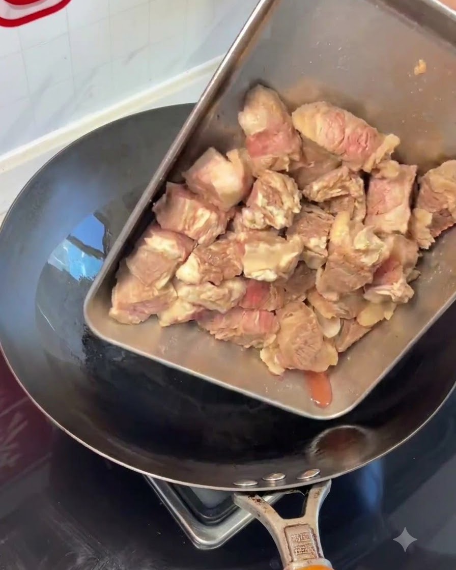 バットから熱した中華鍋へ流し入れられる下ゆで済みの牛肋肉