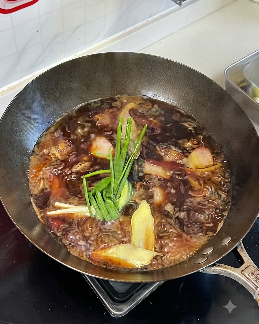 煮立っている中華鍋の牛肉の上にのせられた長ねぎ、生姜、八角やシナモンなどの香辛料