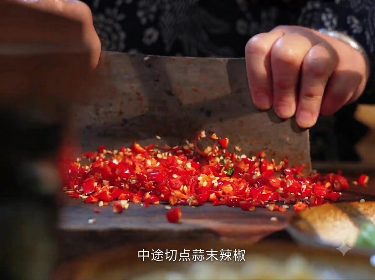 木製のまな板の上で中華包丁を使って刻まれている生の赤唐辛子。