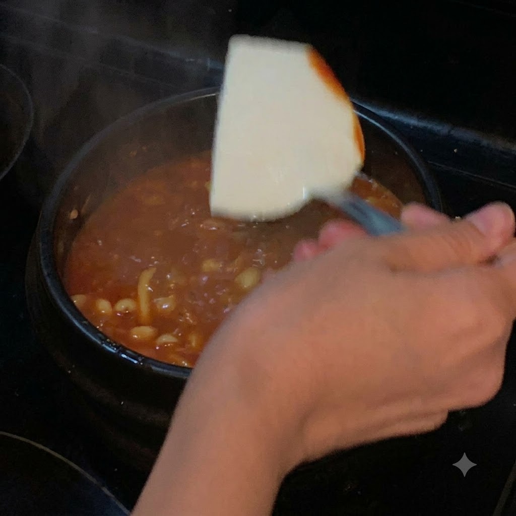 赤い煮込みスープが入った鍋に、ヘラを使って絹ごし豆腐の塊がそっと入れられている様子