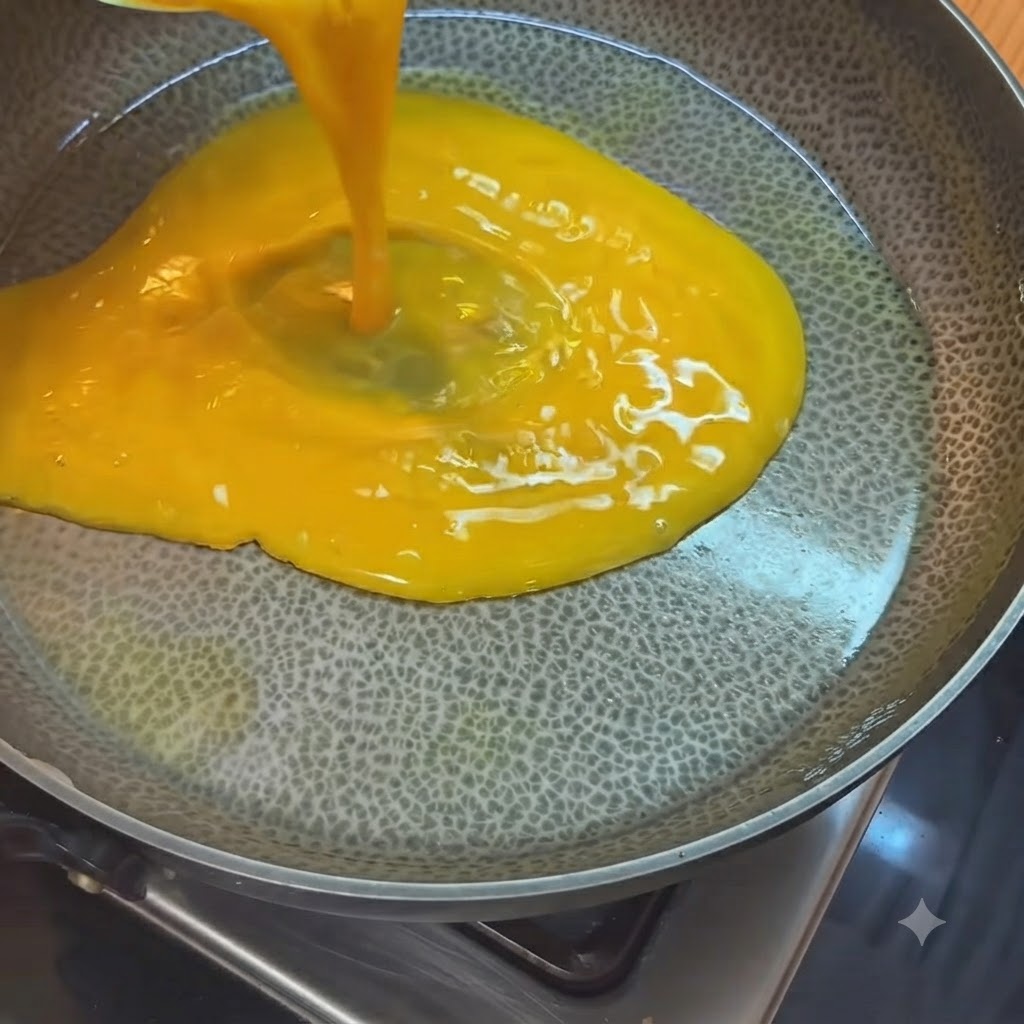 油をひいて熱したフライパンに、計量カップから注がれる鮮やかな黄色の溶き卵。