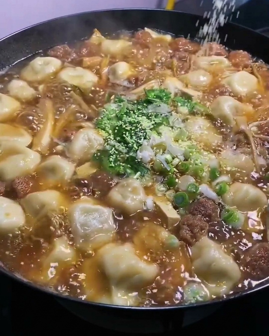 泡立つ中華鍋の上から、チキンブイヨンパウダーが振りかけられているところ。