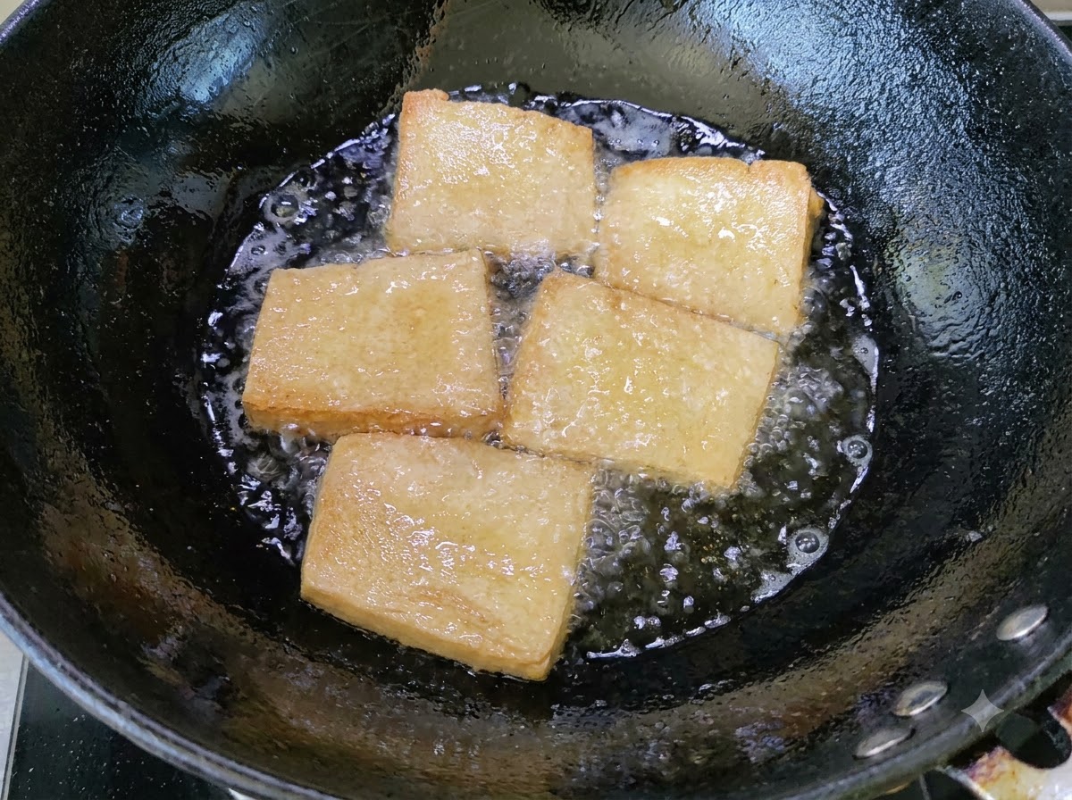 中華鍋の泡立つ油の中で、きつね色に揚げられている豆腐のピース。