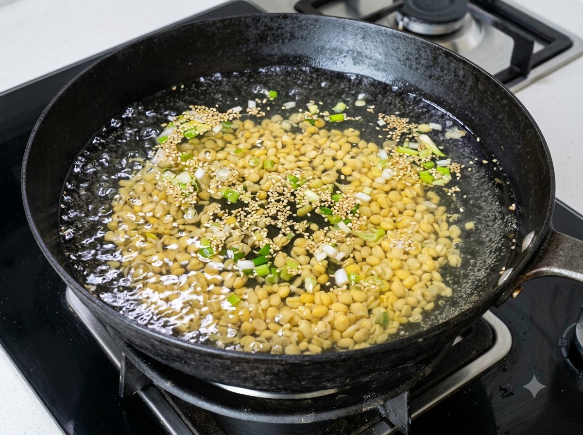 刻みネギの入った中華鍋の沸騰したお湯の中に、大量の黄色い大豆もやしが入っていく様子。
