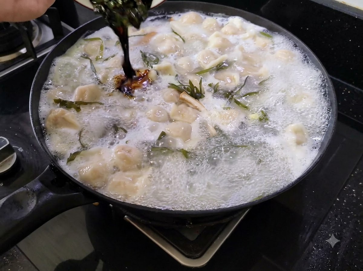 小さな器から、餃子、麺、豆腐、昆布の入った大きな煮込み鍋に濃い色の合わせ調味料を注いでいる様子。