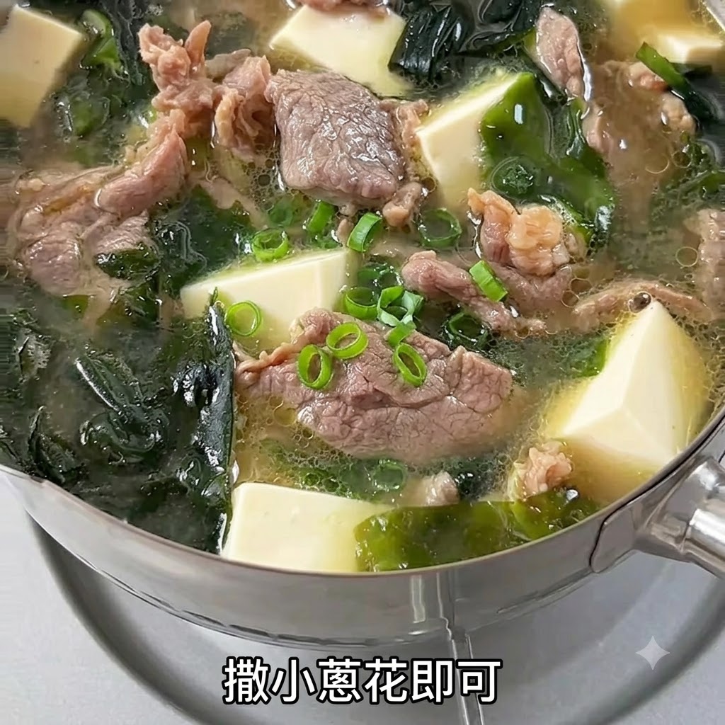牛肉と豆腐のスープが入った湯気の立つ器の上に、刻み立ての青ネギが振りかけられている様子。
