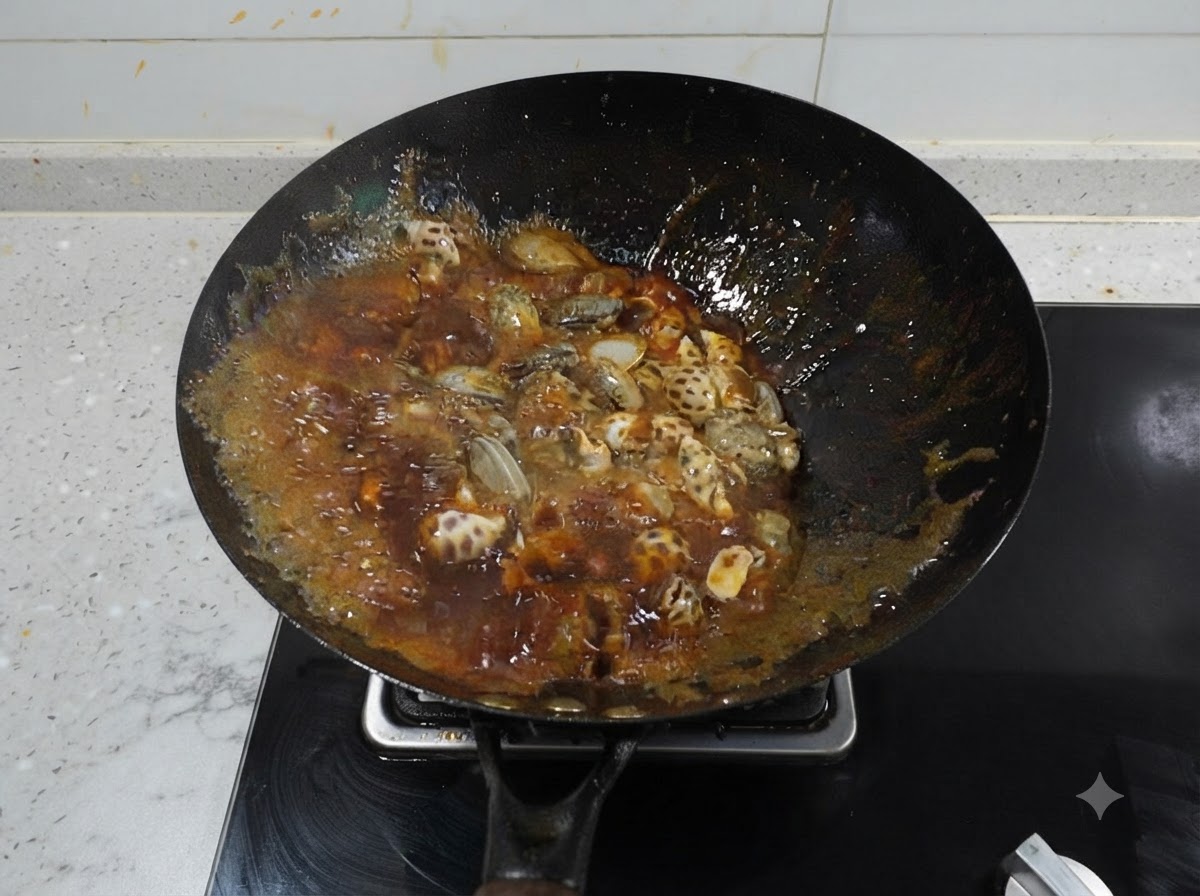 黒い中華鍋の中で、ぐつぐつと煮え立つ濃い赤いスパイシーなスープと、その中のつぶ貝やイイダコ。