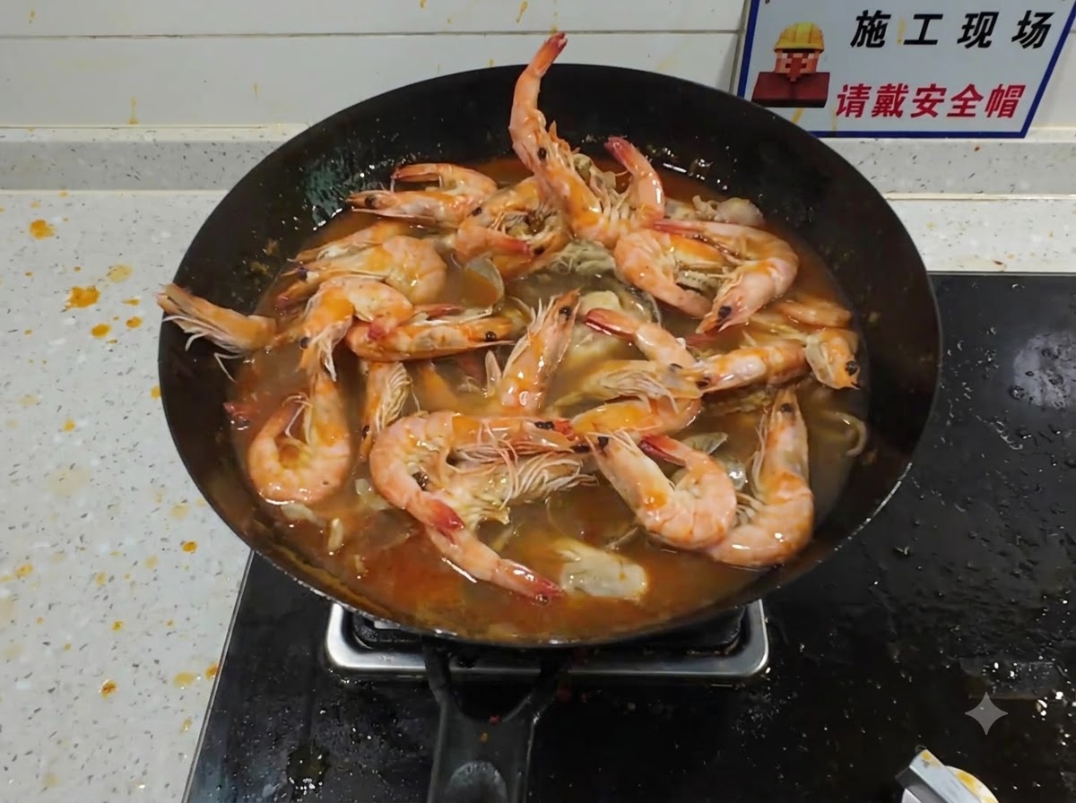 煮えたぎる赤いスープと魚介類が詰まった中華鍋に、大きなロブスターを加えている様子。
