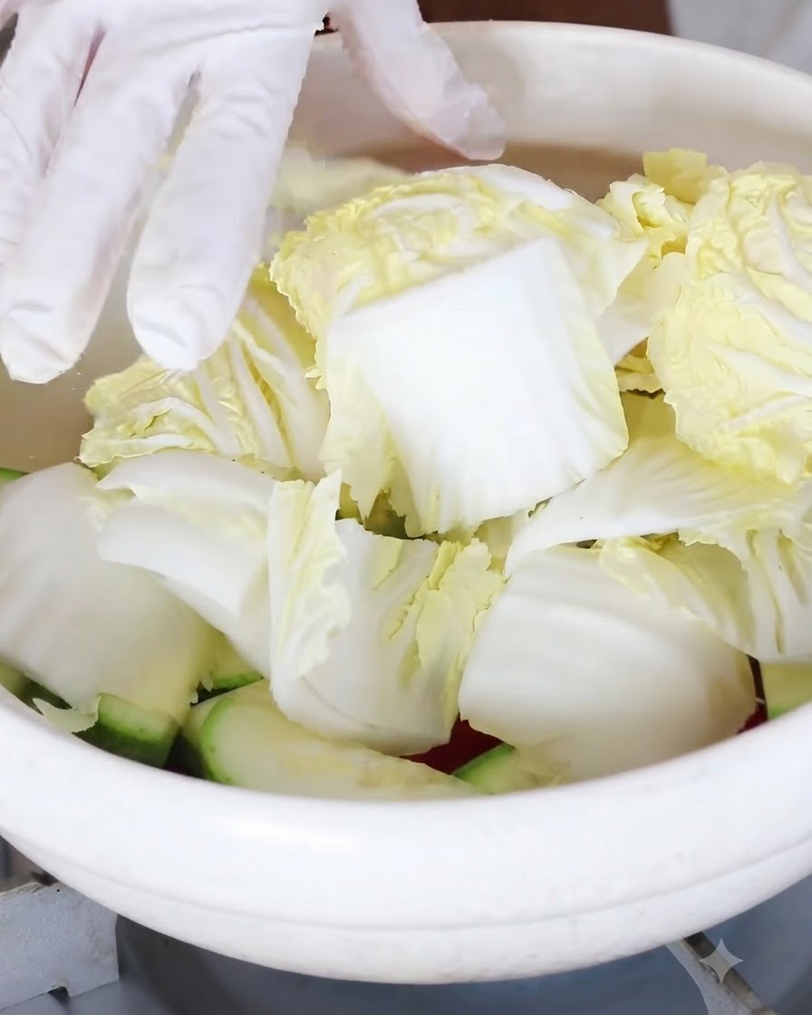 鍋の中の野菜の上に、ざく切りにしたミニ白菜を加えている様子。