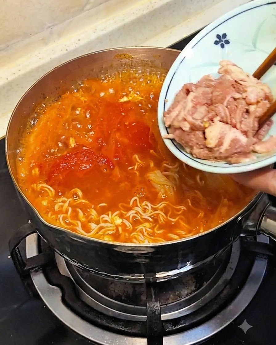 小皿にのった生の牛薄切り肉を、箸で熱いスープに沈める様子。