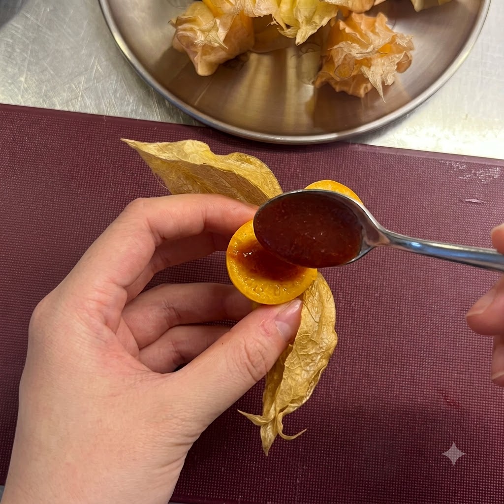 小さなスプーンを使い、スライスしたケープグースベリーの中央にくぼみを作って赤いチリソースを入れているところ。