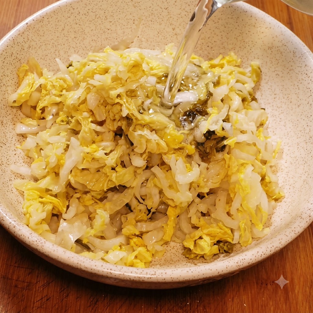 千切りにした高菜が入った陶器のボウルに、水を注いで洗っている様子。