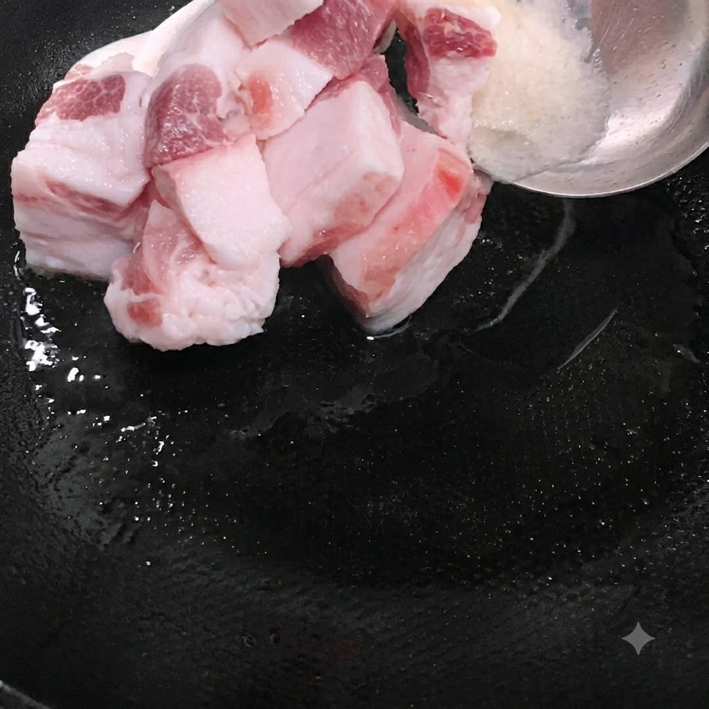溶けたラードと一緒に、脂身の多い豚肉のスライスを中華鍋に入れている様子。