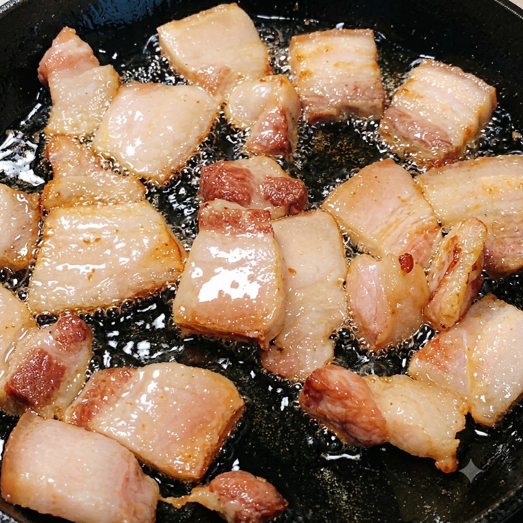 溶け出した脂の中で、薄切りの赤身豚肉が炒められきつね色に色づいている様子。