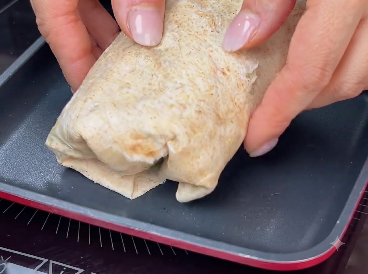 巻いたラップを熱したフライパンで焼き、きつね色の焼き色をつけている様子。