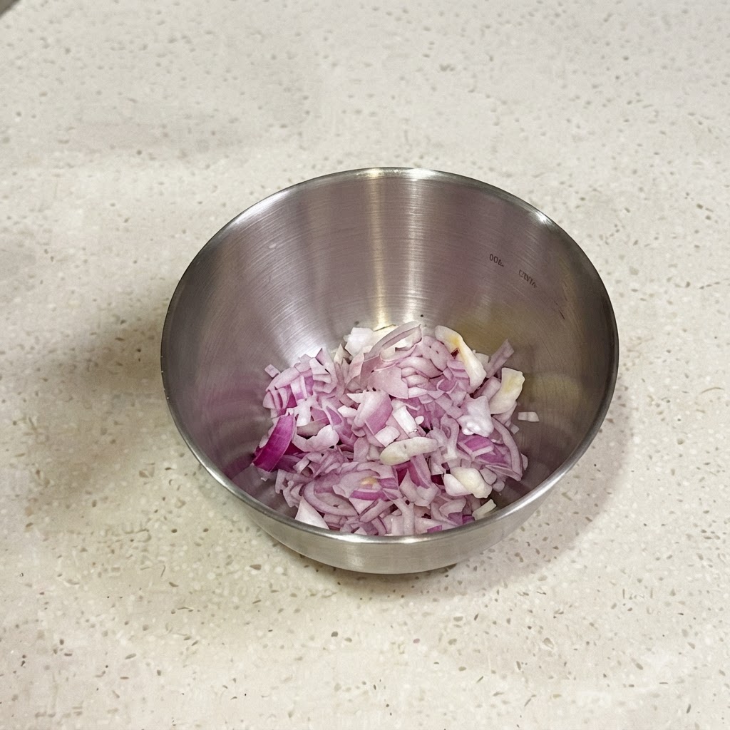 調味料と混ぜ合わせるために、細かく刻んだ赤エシャロットと青ネギが入った小さな金属製のボウル。