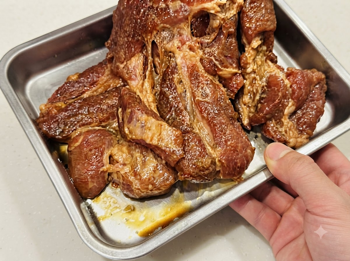 ホイルを敷いた金属製ベーキングトレイの中に、豚肉を平らに一重で並べている様子。