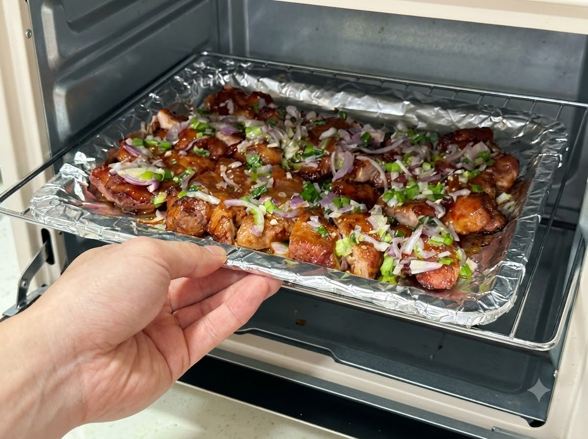 ソースをかけた豚肉の切り身が載ったベーキングトレイをエアフライヤーに戻し入れる様子。