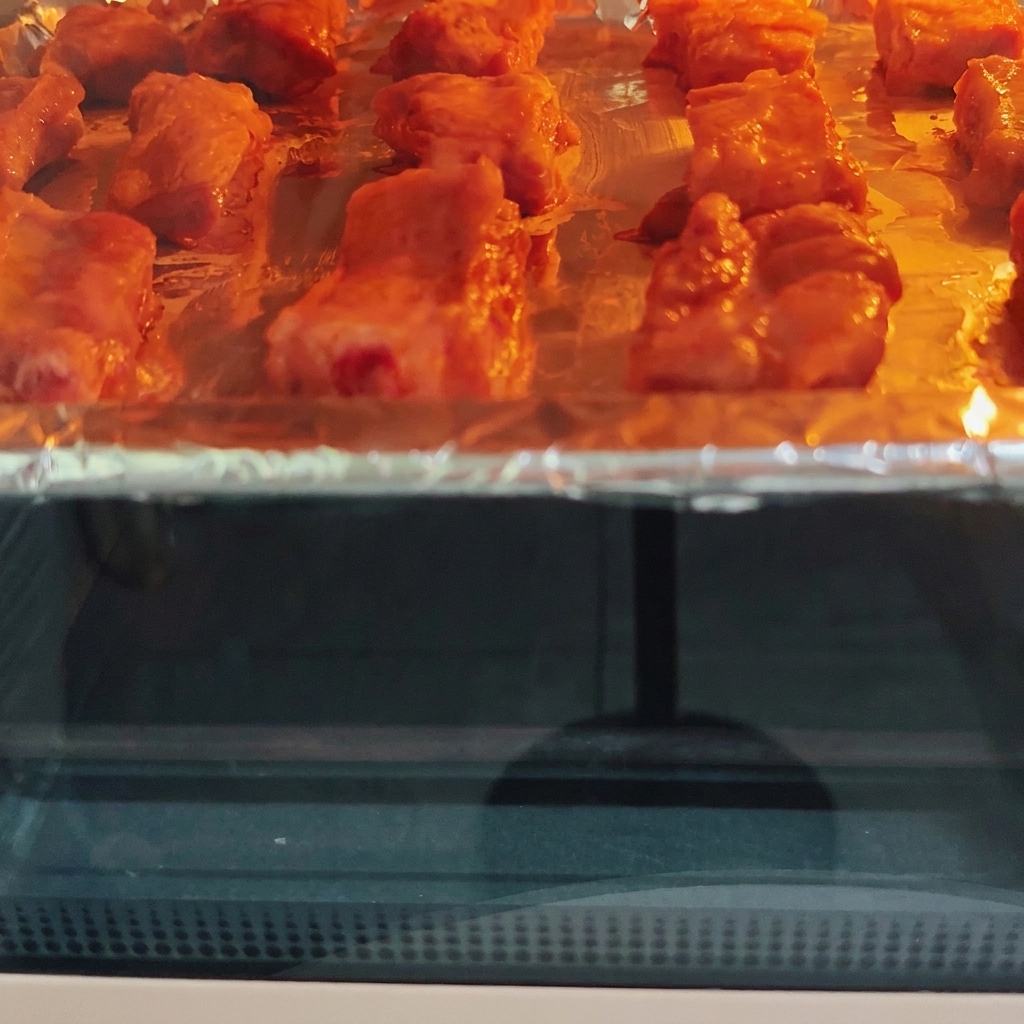 熱いオーブンの中でローストされている豚スペアリブ。加熱ヒーターの下で表面に焼き色がついている様子。