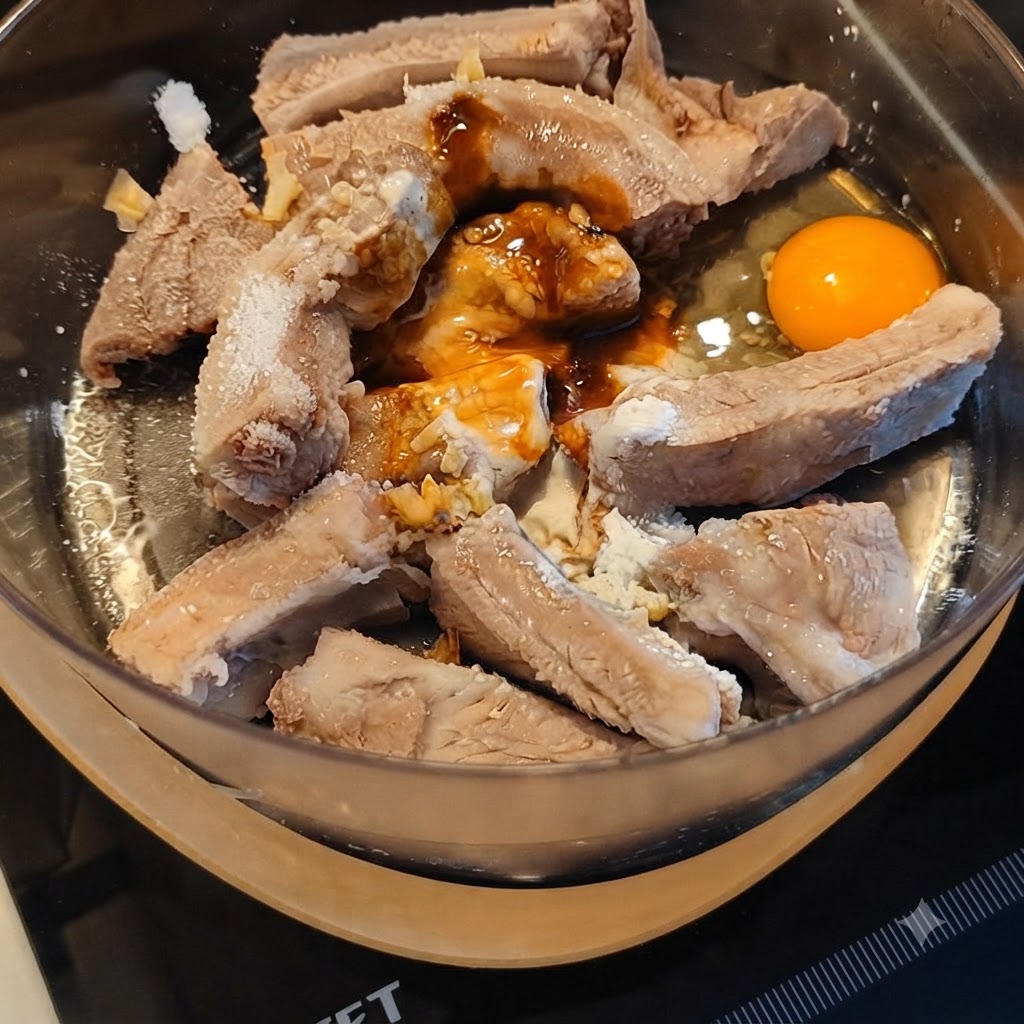 ボウルの中でさまざまな調味料と割った卵を使って豚スペアリブを下味に漬け込んでいる様子。