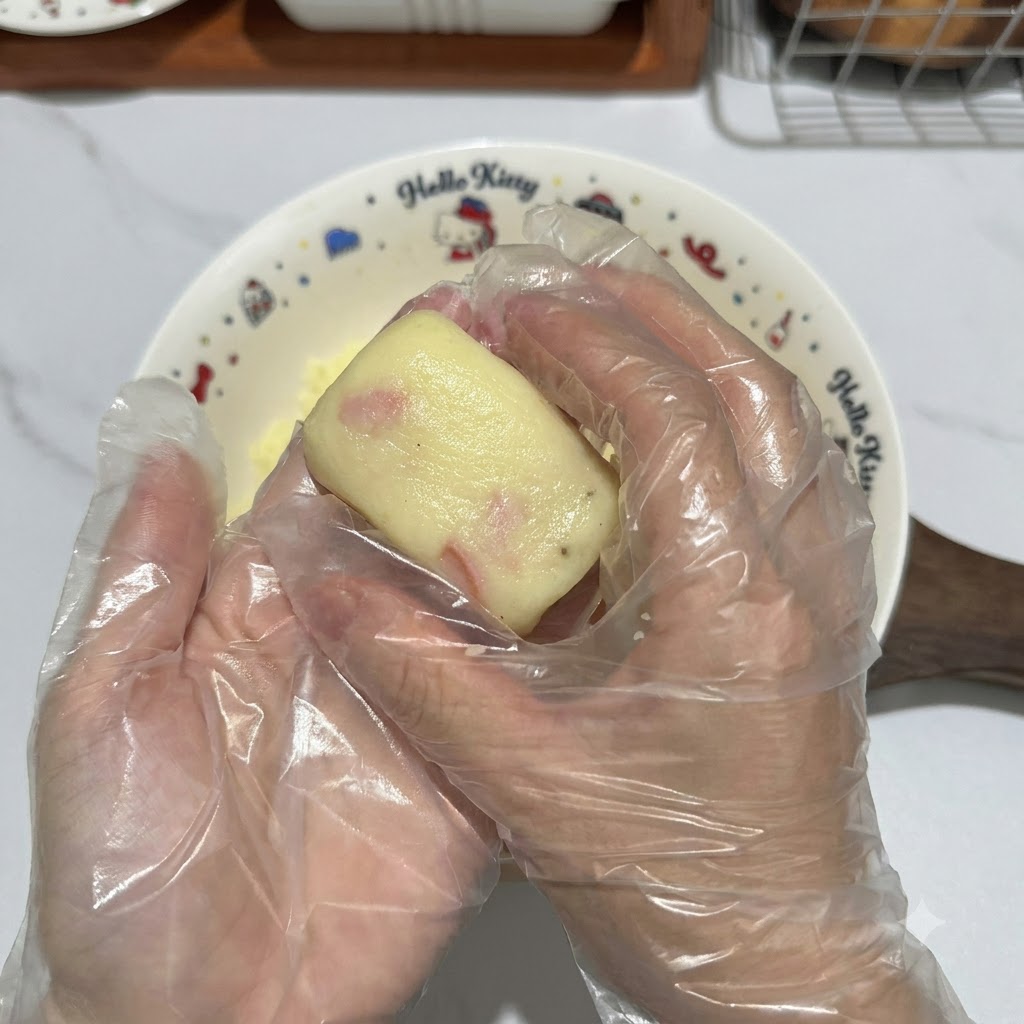 手袋をした手がポテト生地の塊をきれいな長方形のパティに整えている様子。