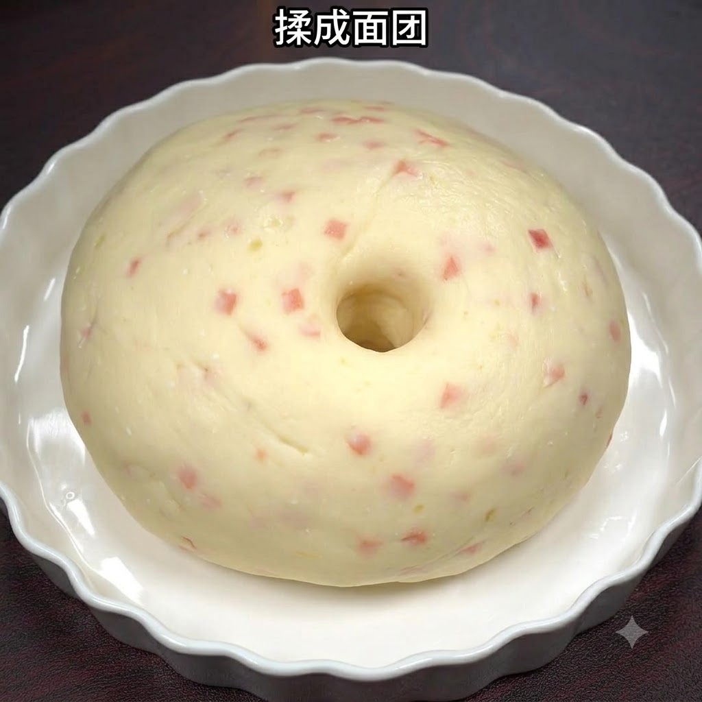 白いセラミック皿の中で、ハムのピースが混ざったなめらかなポテトとハムの生地がボール状にまとめられている様子。