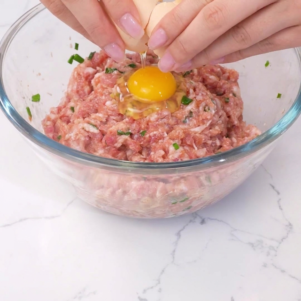 味付けされた肉ダネの中心に卵が割り入れられている様子。